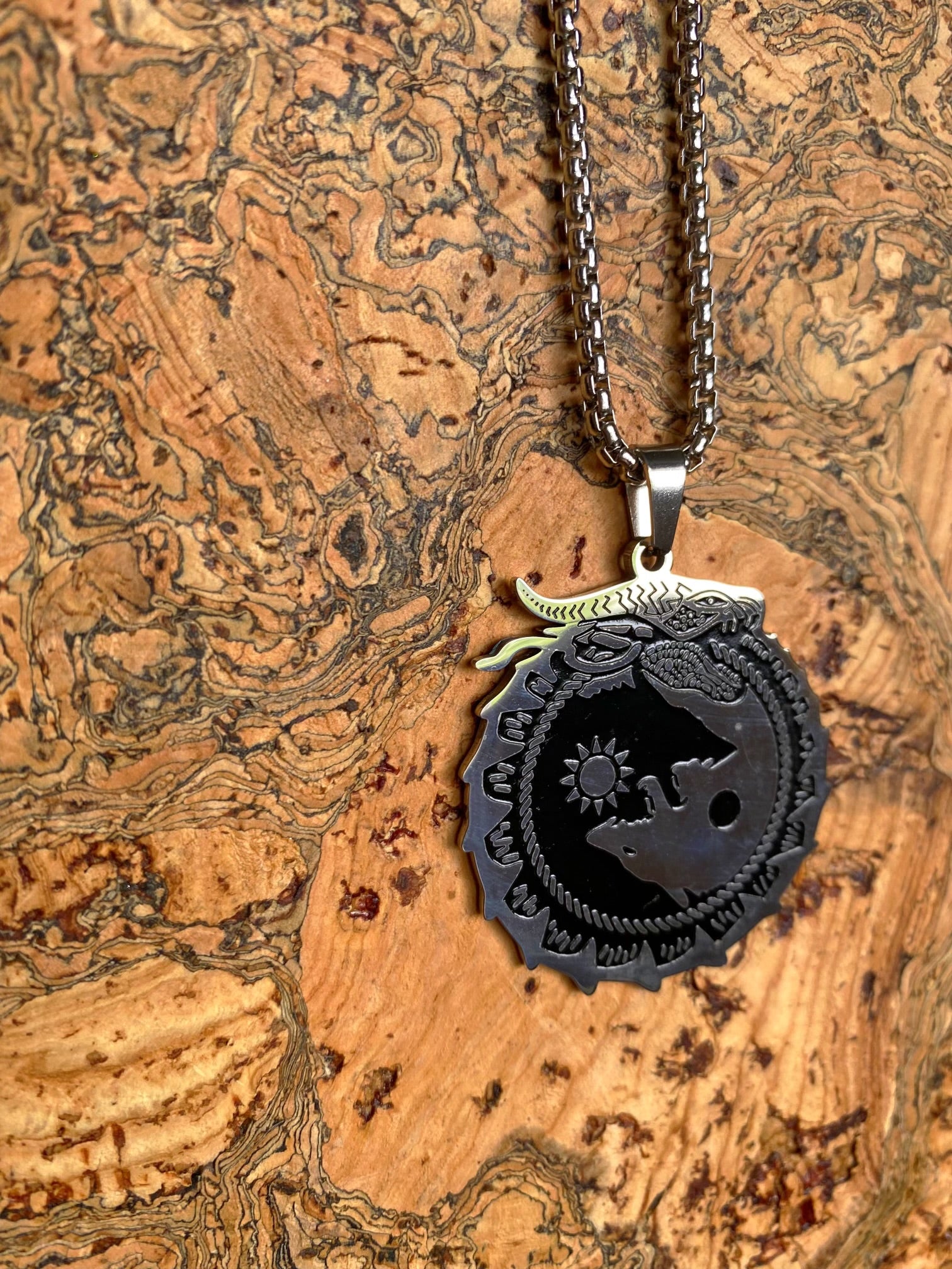 A silver wolf Viking necklace with a large spherical pendant, embossed Viking wolf design dangling from a silver chain.