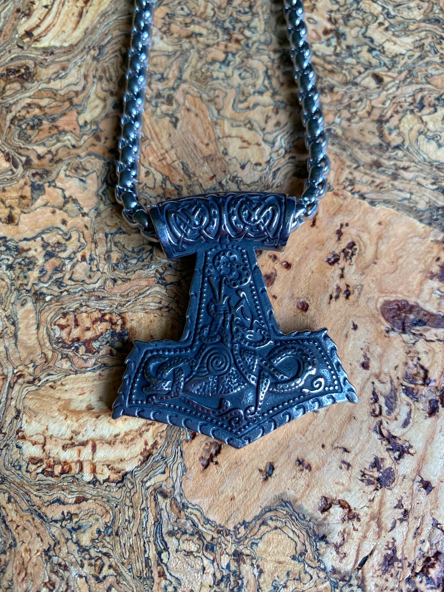 A stainless steel Thor's Hammer necklace with a Valknut symbol and Norse skull designs.