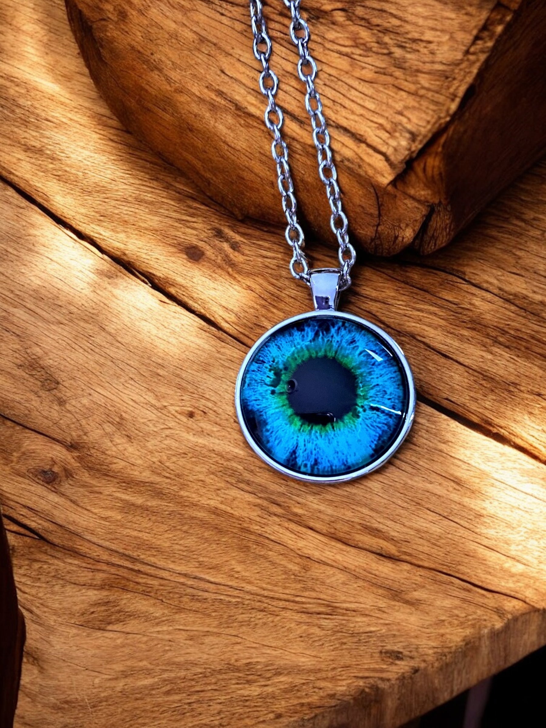 A stainless steel Viking necklace with a pendant depicting Odin's eyeball, displayed on a wooden surface.